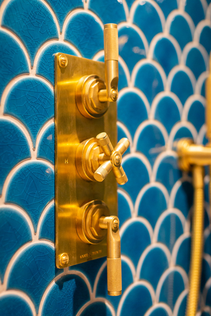 Brass shower valve on teal scalloped tile