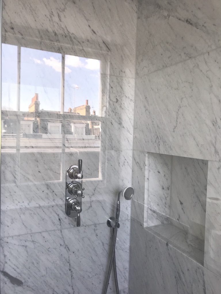 Carrara marble tiled shower with recessed niche