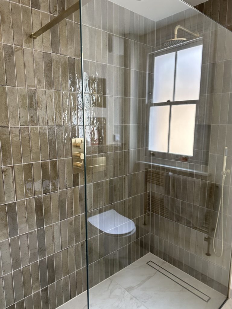 Tiled walk-in shower with brushed brass fittings