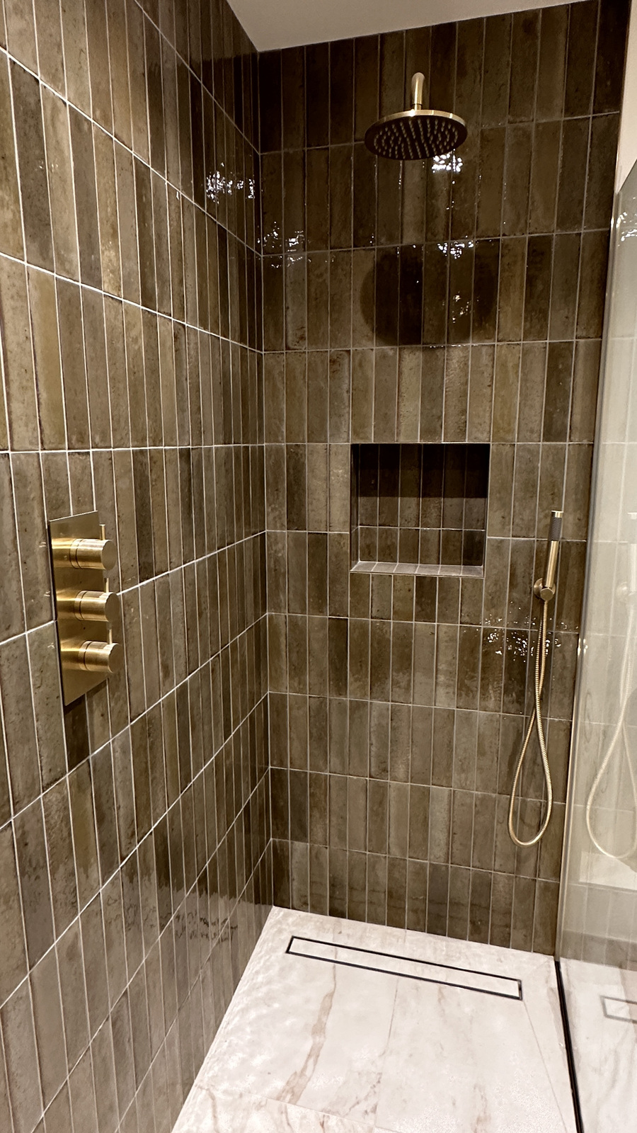 Vertical tile shower with brass fittings and niche