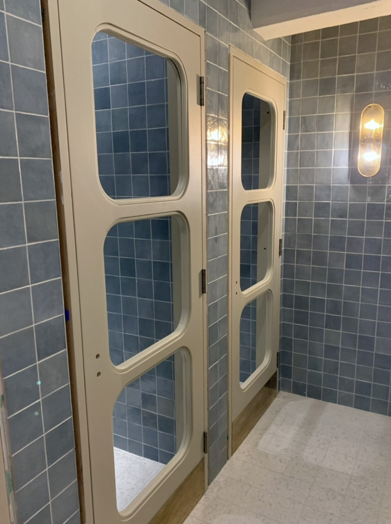 Blue tiled shower stalls with glazed doors